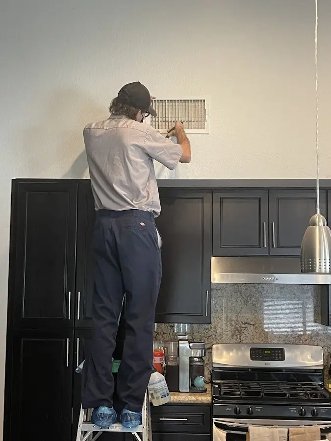 Technician inspecting an air vent during HVAC service in Northbridge